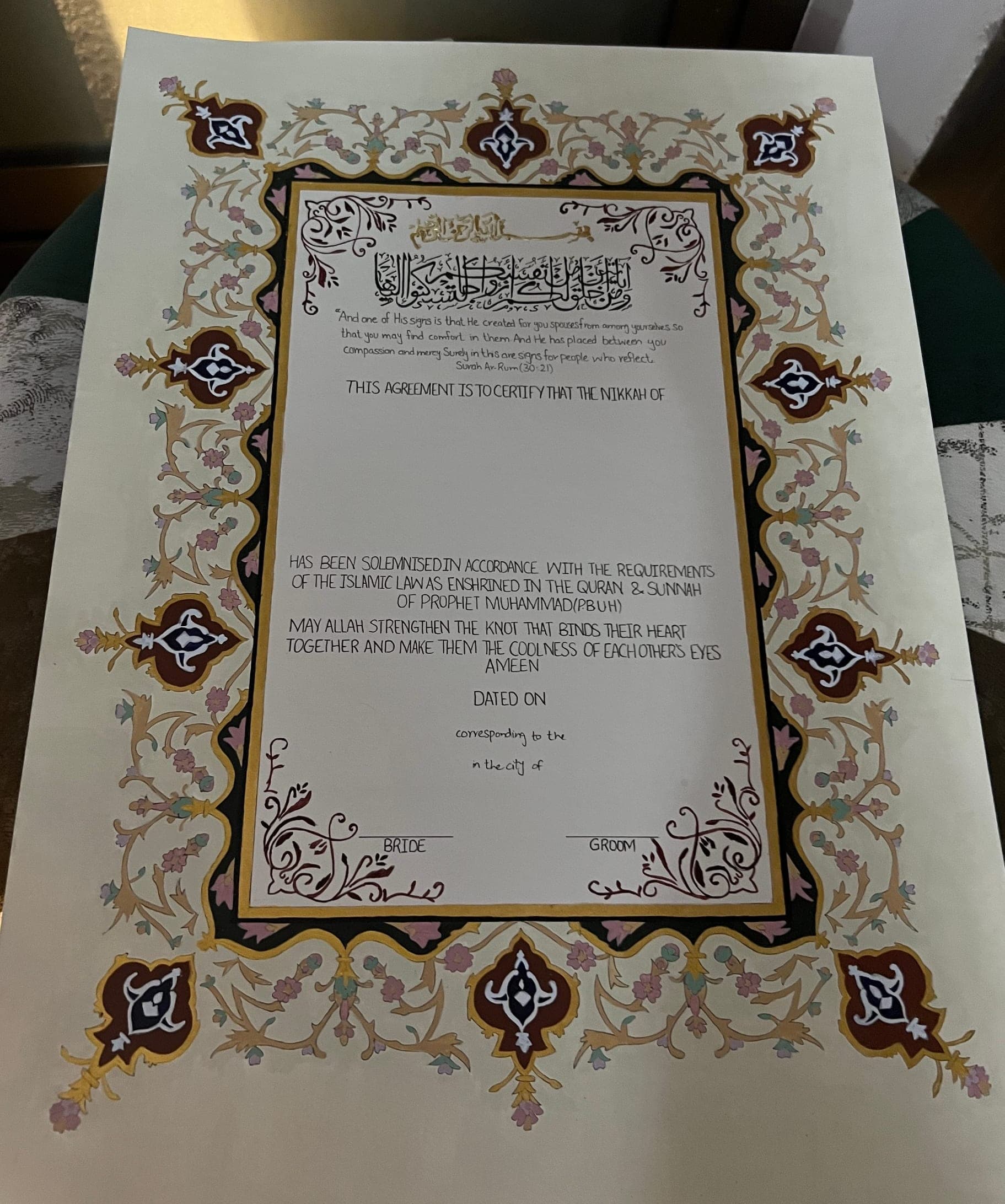 The full painted border of a Nikkah Nama, with burgundy and navy cartouches at each corner and edge